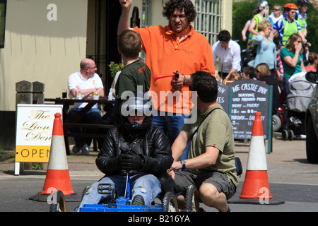Soapbox with driver and two pushers waits with a race official at the start Stock Photo