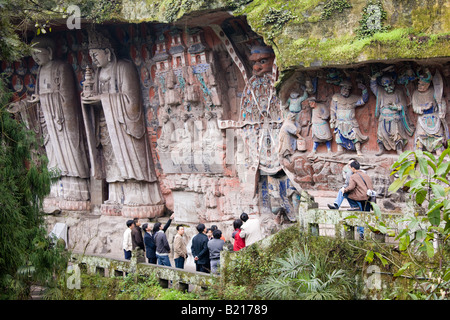 Tourist look at Anicca God of Destiny holding wheel of life Dazu rock carvings Mount Baoding China Stock Photo