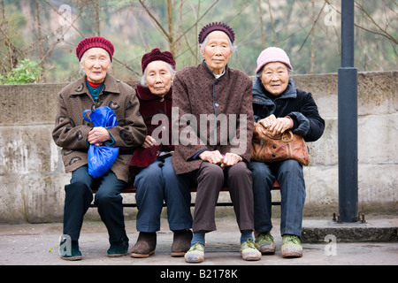 Elderly Chinese women sit together on a bench in Chongqing China Stock Photo