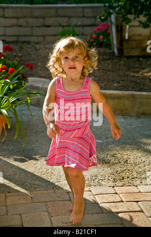 A confident two year old girl walks in the garden of her home in Southern California Stock Photo