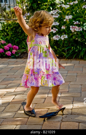 A two year old girl tries on her mother s shoes at home in Southern California Stock Photo