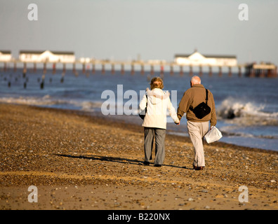 Elderly couple walking on the beach on sunny winters day Stock Photo