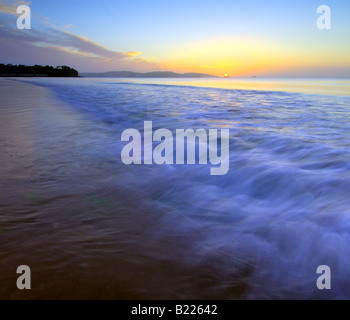 The breaking dawn on the foreshore at Goodrington Sands in South Devon with the dawn light reflecting on the breaking waves Stock Photo