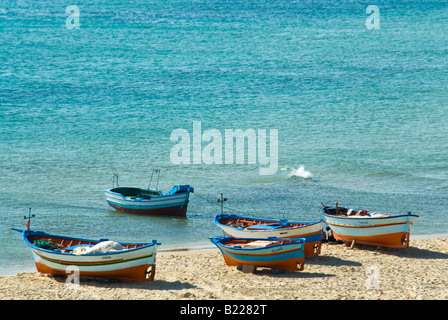 Horizontal elevated view of several traditional local fishing boats dragged up onto the beach in the late afternoon Stock Photo