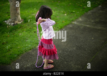 Girl aged four learning to skip Note trademarked Disney skipping rope Stock Photo