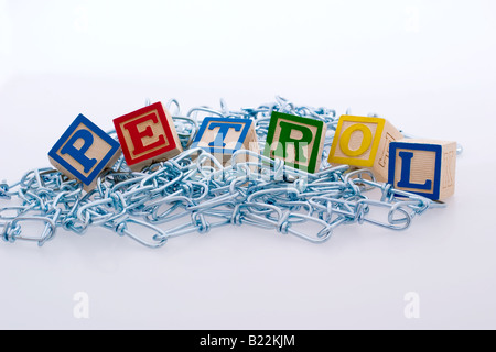 Children's blocks spelling out 'petrol' atop a pile of metal chains Stock Photo