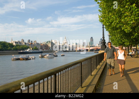 Couple strolling along the River Thames with the City and St Paul s Cathedral in the distance London UK Stock Photo