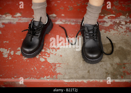 Six year old boy tries to tie laces on his new shoes Stock Photo