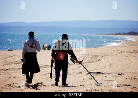 Men with metal detector search for hidden valuables on the beach at Catania, Sicily, Italy Stock Photo