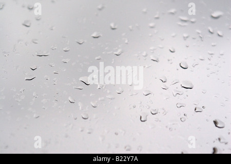 Raindrops gather on a window pane on a grey wet overcast day. Stock Photo