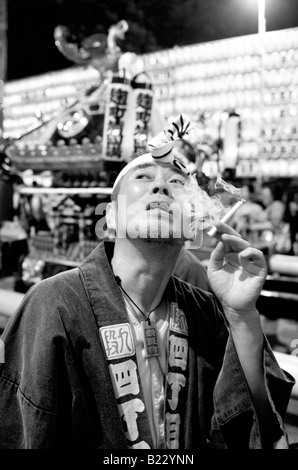 Japanese man in traditional costume smoking a cigarette at the Mitama Festival in Tokyo Japan Stock Photo