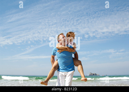 Man piggybacking woman on beach Stock Photo