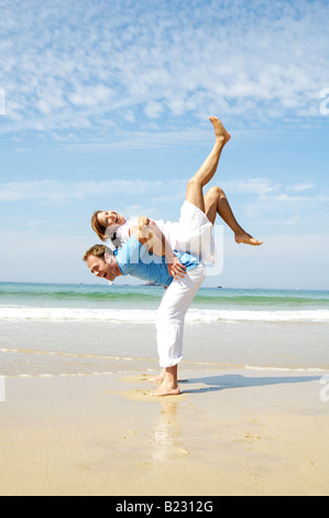 Man piggybacking woman on beach Stock Photo
