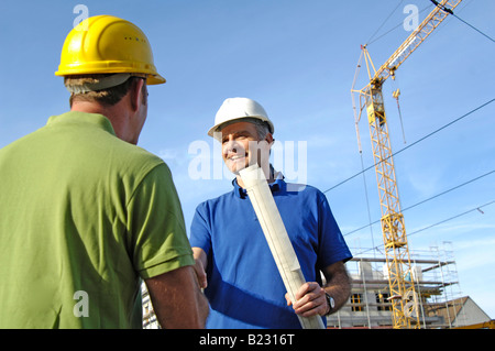 Two male architects shaking hands at construction site Stock Photo