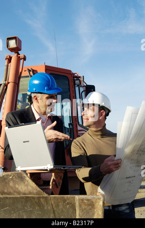 Two male architects talking to each other at construction site Stock Photo
