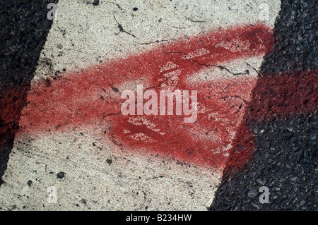 Close up of painted red arrow on a white lane marking on a conglomerate concrete street Stock Photo
