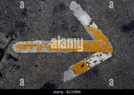 Close up of a yellow and silver arrow on a concrete sidewalk Stock Photo