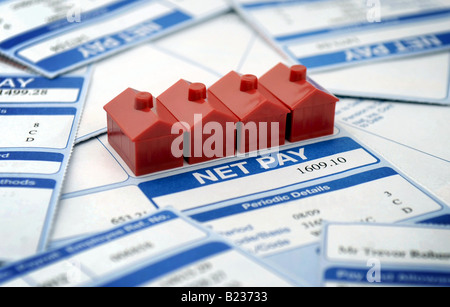 ROW OF MODEL MONOPOLY HOUSES WITH BRITISH PAYSLIPS RE HOUSE BUYERS MARKET WAGES NET PAY INCOME RECESSION CREDIT CRUNCH ETC,UK. Stock Photo