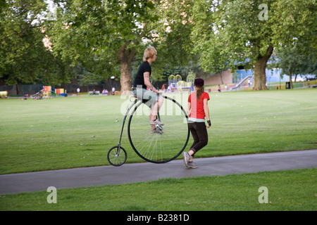 a woman on a penny farthing bicycle in london fields london Stock Photo