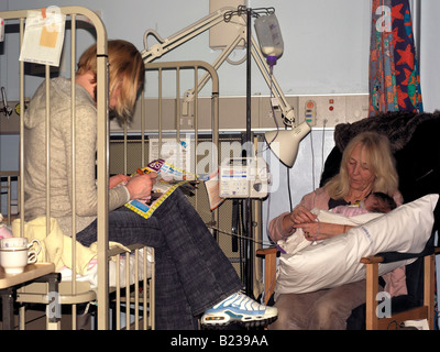 Grandmother and Mother Visiting Sick Baby in Hospital in the Childrens Ward Stock Photo