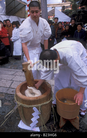 Priests from Ebisu Shrine in Kyoto are kneading glutinous rice into paste the traditional way for making mochi cakes at New Year Stock Photo