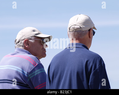 Two old men wearing baseball caps, taken from behind. Stock Photo