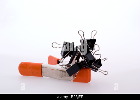 Black binder clips joined together atop a orange metal studio clip Stock Photo