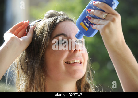 Teenage girl applying sun tan lotion to her face Stock Photo