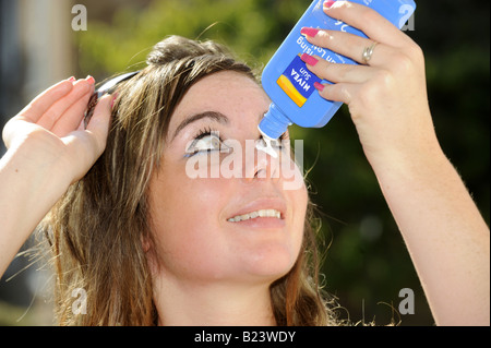 Teenage girl applies sun tan lotion to her face Stock Photo