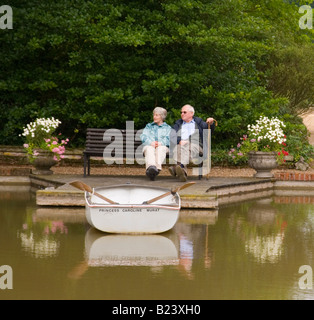 Couple Relaxing By The Lake At Open Gardens At Redisham Hall In Suffolk Stock Photo
