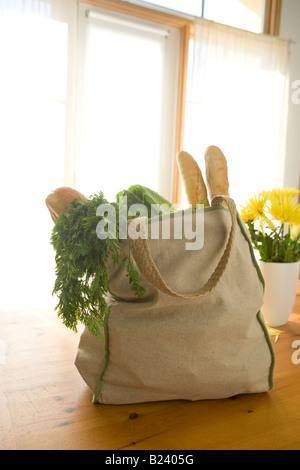 reusable grocery bag full of food on table with bright window light Stock Photo