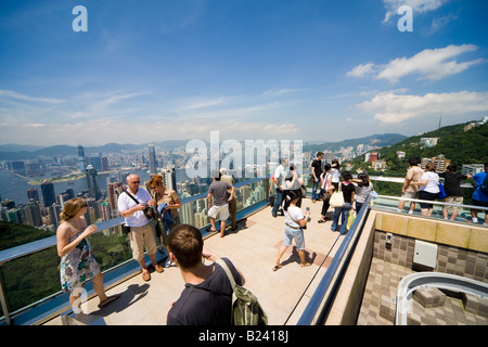 Tourists taking pictures and looking at Hong Kong Panorama from the viewing terrace of the Victoria Peak Tower on a clear day.