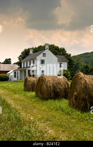 Charming white rural farmhouse in hay field Stock Photo