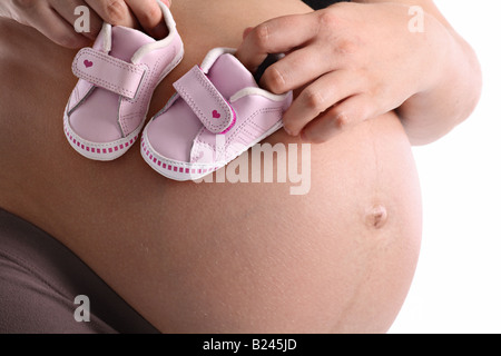 Pregnant woman with little baby shoes on her belly Stock Photo