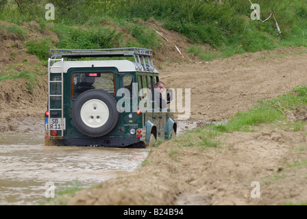 Land Rover driving off road through a flooded dirt road in Bining, France. Stock Photo