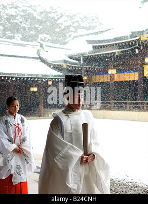 A Shinto priest particpating in a wedding ceremony with a background of snow falling at the Meiji Jingu Shrine in Tokyo, Japan Stock Photo