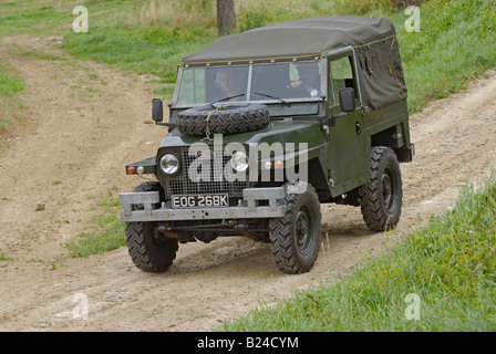 Early Land Rover Lightweight Series 2a with headlamps in the radiator panel driving along a dirt road in Bining, France. Stock Photo