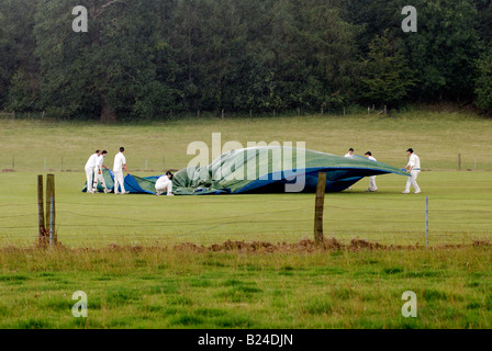 Village cricket players putting on covers in driving rain, Ragley Hall, Warwickshire, England, UK Stock Photo