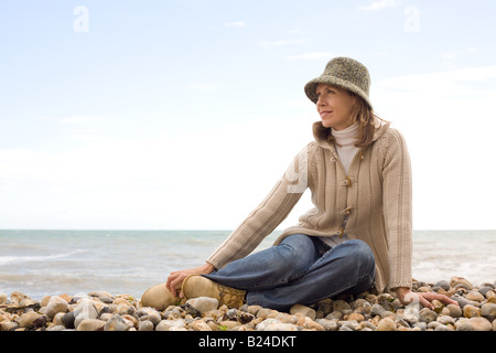 Woman sitting on pebble beach Stock Photo