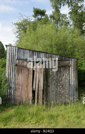 An old dilapidated / ramshackle shed of corrugated iron and wood stands the grounds of a Scottish garden. Stock Photo