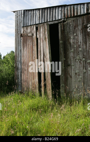 An old dilapidated / ramshackle shed of corrugated iron and wood stands the grounds of a Scottish garden. Stock Photo