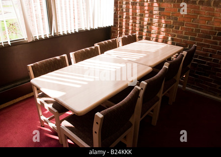 Tables and chairs next to a brick wall at a library illuminated by sunlight Stock Photo