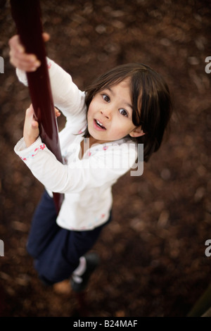 Girl aged five plays in adventure playground sliding down pole Stock Photo