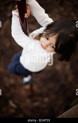 Girl aged five plays in adventure playground sliding down pole Stock Photo