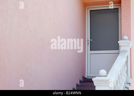 Entrance door with a pink wall a ladder and hand rail Stock Photo