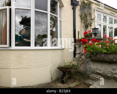 Woman working on a Computer in a surburban House seen through the bay window Stock Photo