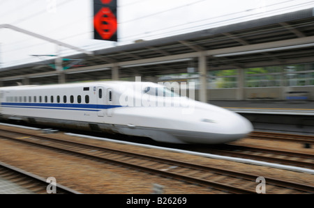 A Japanese Bullet Train (Shinkansen) passing through a railway station Stock Photo