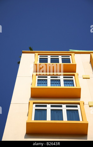 Modern living accommodation in Singapore. The yellow block of flats stands highlighted against a blue sky. Stock Photo
