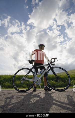 Front view of a man standing on road with bicycle