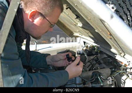 Mechanic checking the engine on a grey 1950's Land Rover Series One 86 inch Station Wagon. Stock Photo